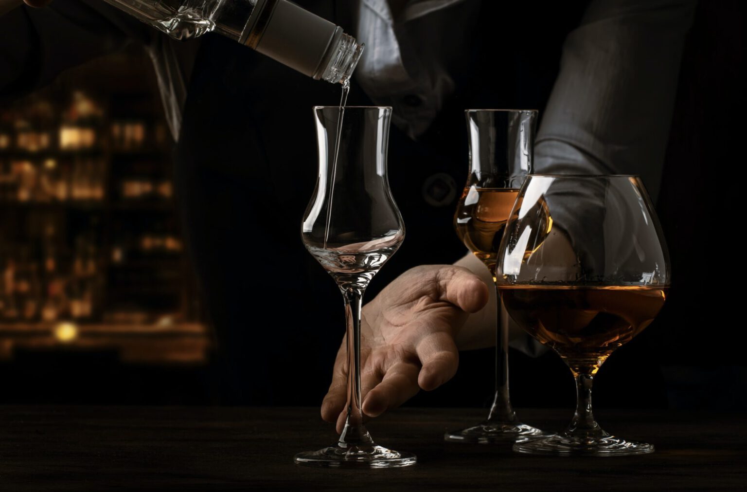 Der Barkeeper gießt Grappa in ein kleines Schnapsglas